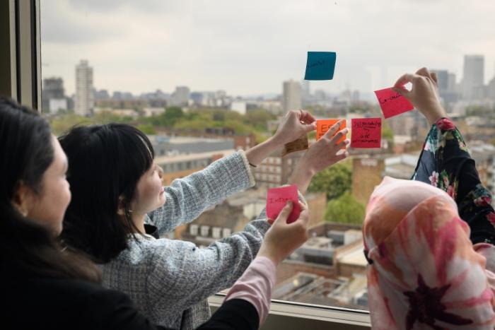 Three students looking at post-it notes stuck to a window