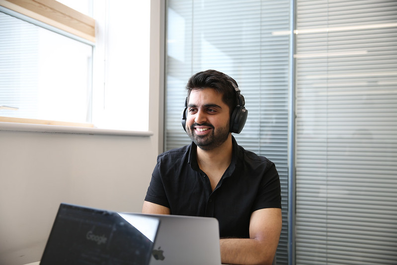 A student wearing headphones smiling at the computer