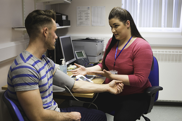 Photograph of a clinician taking a patients blood pressure during a consultation at a GP practice