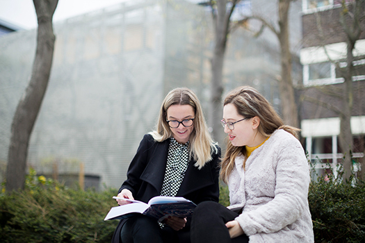 Queen Mary Law students reading a book outside on campus
