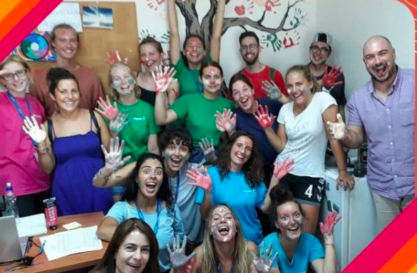 A group of people smiling with paint on their hands after making a mural
