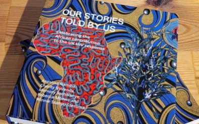 The cover of the book 'Our Stories Told by Us: Celbrating the African contribution to the UK HIV response'. The cover includes an outline of Africa in red on a blue and yellow swirled patterned cover.