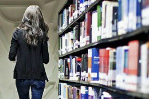 student walking alongside library shelf
