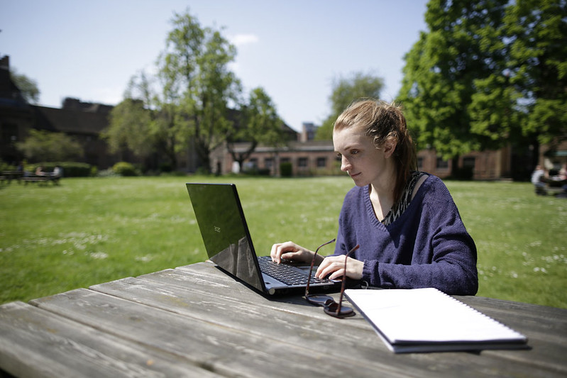 Student using a computer on a table outdoors