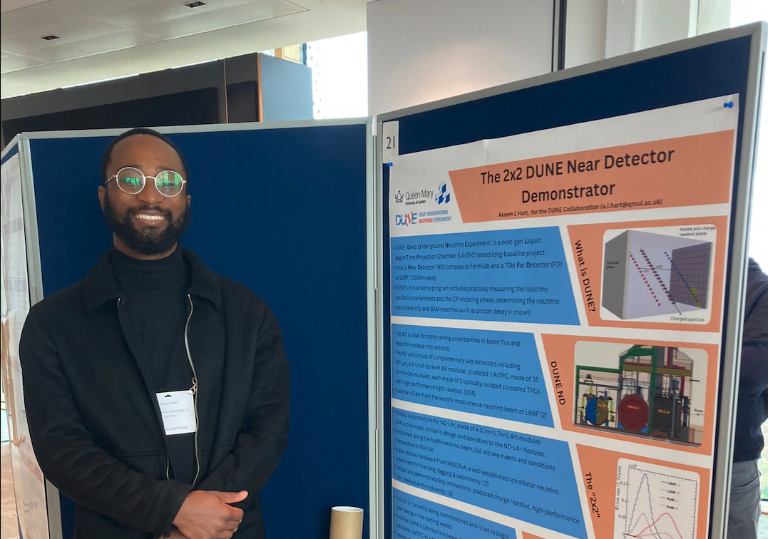A photograph of Akeem Hart, a PhD student at the Particle Physics Research Centre (PPRC) at Queen Mary University of London.