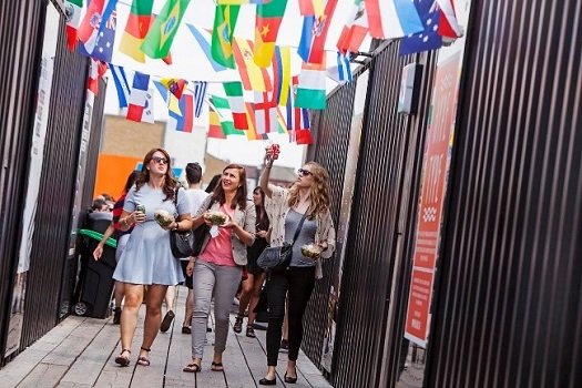 students on the Mile End Campus of Queen Mary University walking under flags of bunting decorated with international flags
