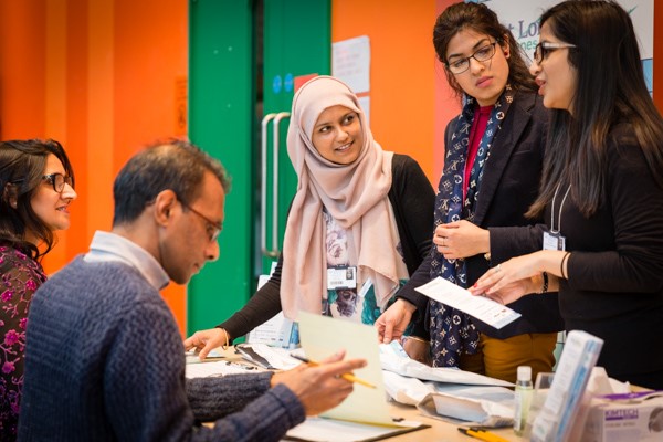 Five WIPH researchers gather around a desk in a community centre, in preparation for recruiting participants for their study into diabetes in British Pakistani and Bangladeshi people.