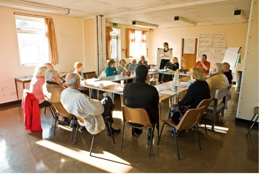 Elderly people having a meeting around a large table