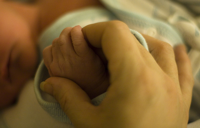 Parent holding a newborn's hand