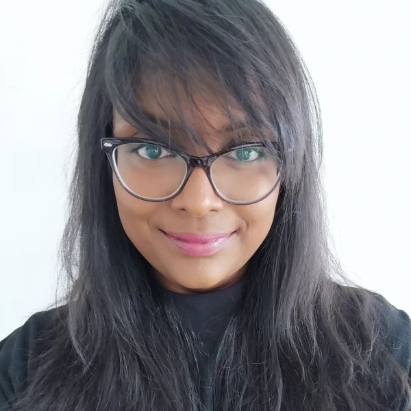 Headshot of Dr Manesha Peiris. She is wearing a black roll neck jumper with black framed glasses.