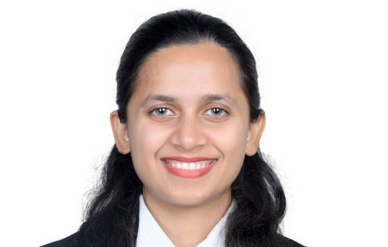 Professional headshot of Sneha Palekar smiling against a blank white background.