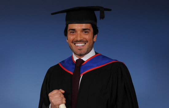 Professional studio portrait of a man in a graduation cap and gown.