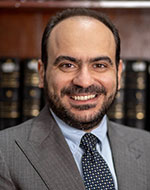 Dr Amir Nabil Ibrahim in a suit, in front of a book shelf