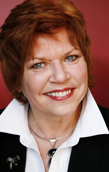 Prof Anne Flanagan in white shirt in front of red background