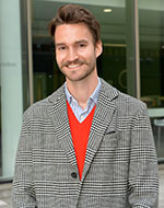 Felix Wahler smiling, wearing a red jumper and plaid jacket