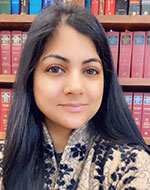 Meenakshi Slathia standing in front of legal books