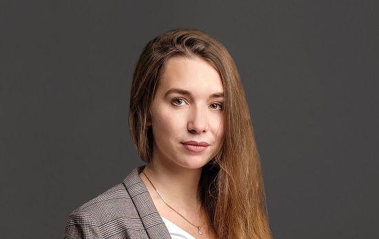 Young woman with long hair over one shoulder turning to camera