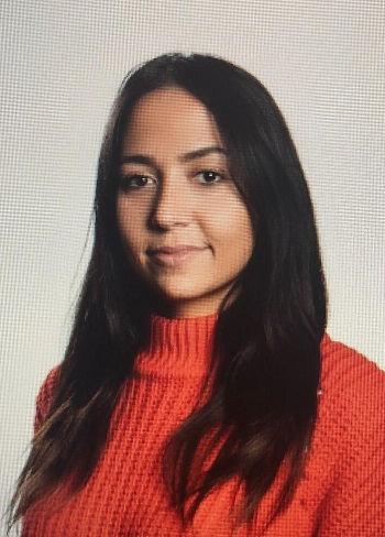 Alumna with long dark hair in orange sweater