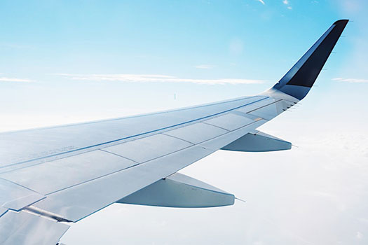 A wing of a commercial plane flying in a blue sky