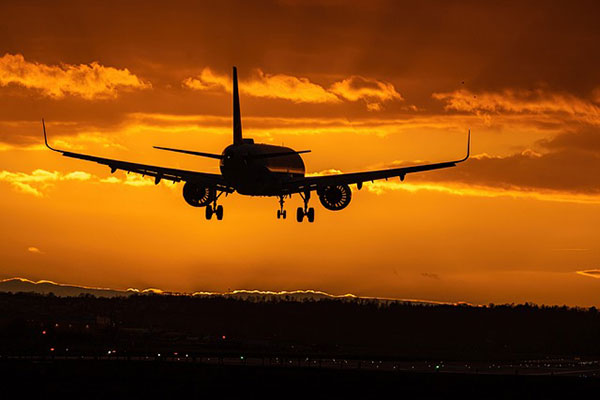 A plane landing against a sunset