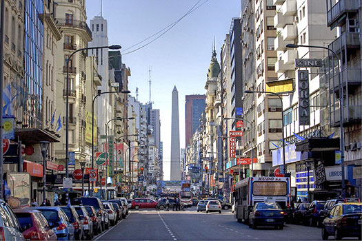 A street in Buenos Aires lined with cars and an Obelisk in the background