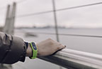 Runner's hand leaning on a metal railing wearing a lime green smartwatch