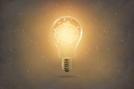 Lightbulb emitting a yellow light with a brain inside