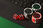 Poker chips and a dice sitting on a laptop keyboard
