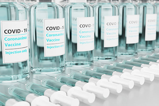 A row of Covid-19 vaccine vials with syringes