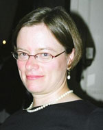 Julia Hornle wearing glasses, a black jumper and pearls