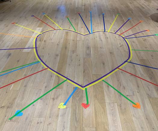 A heart drawn on a wooden floor, with coloured arrows radiating from it
