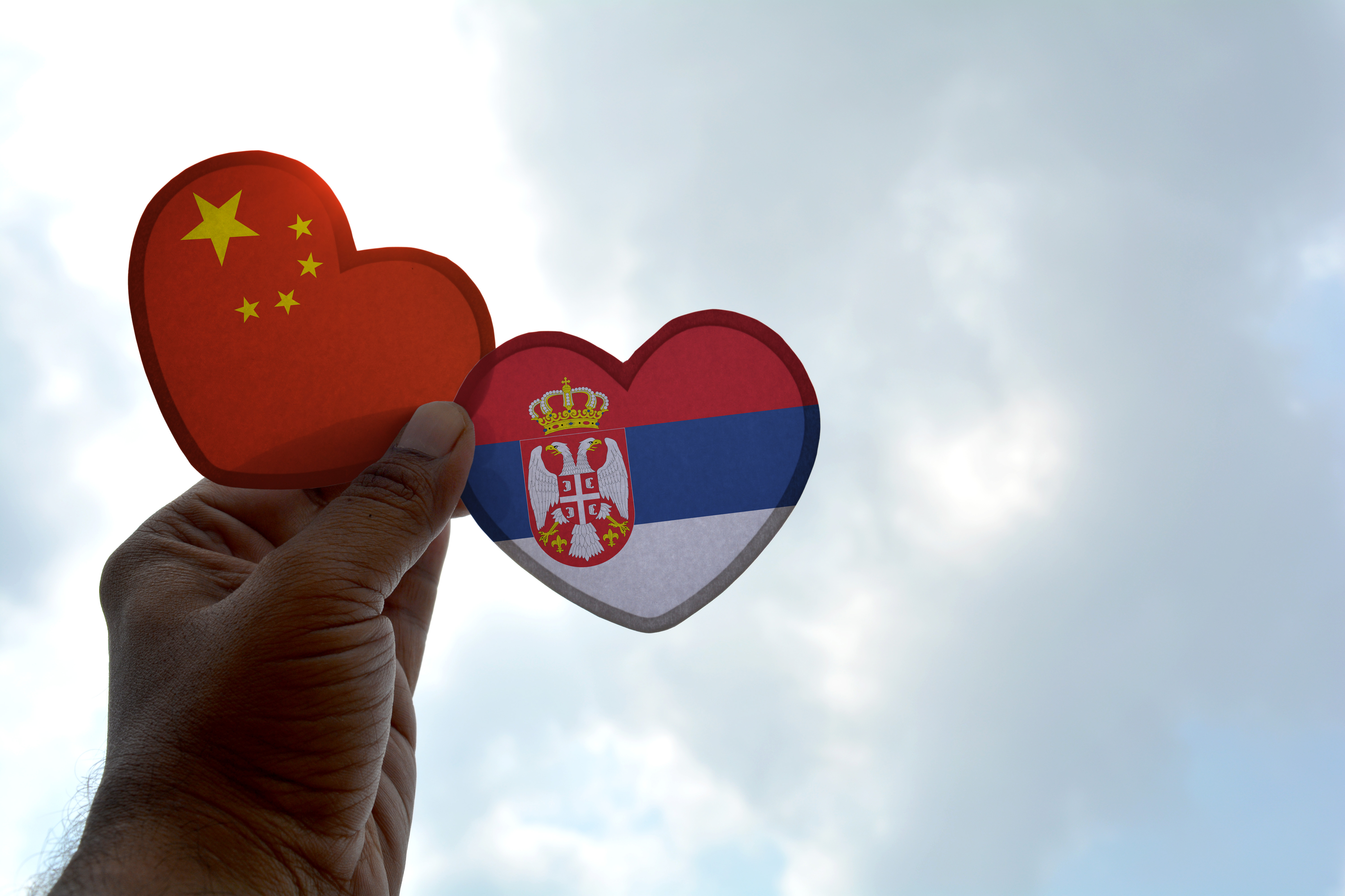 Hand holding heart-shaped Chinese and Serbian flags