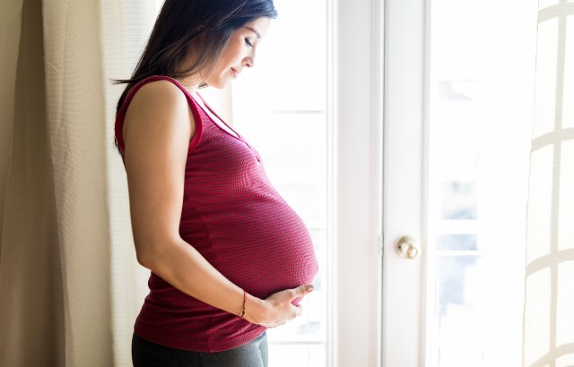 A pregnant woman looking at her bump