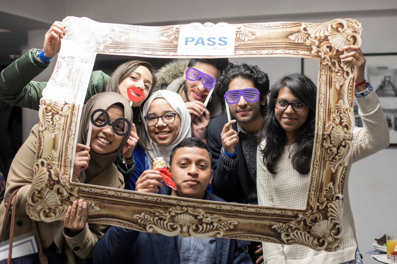 PASS Students - students holding cardboard picture frame, with student faces appearing as picture.