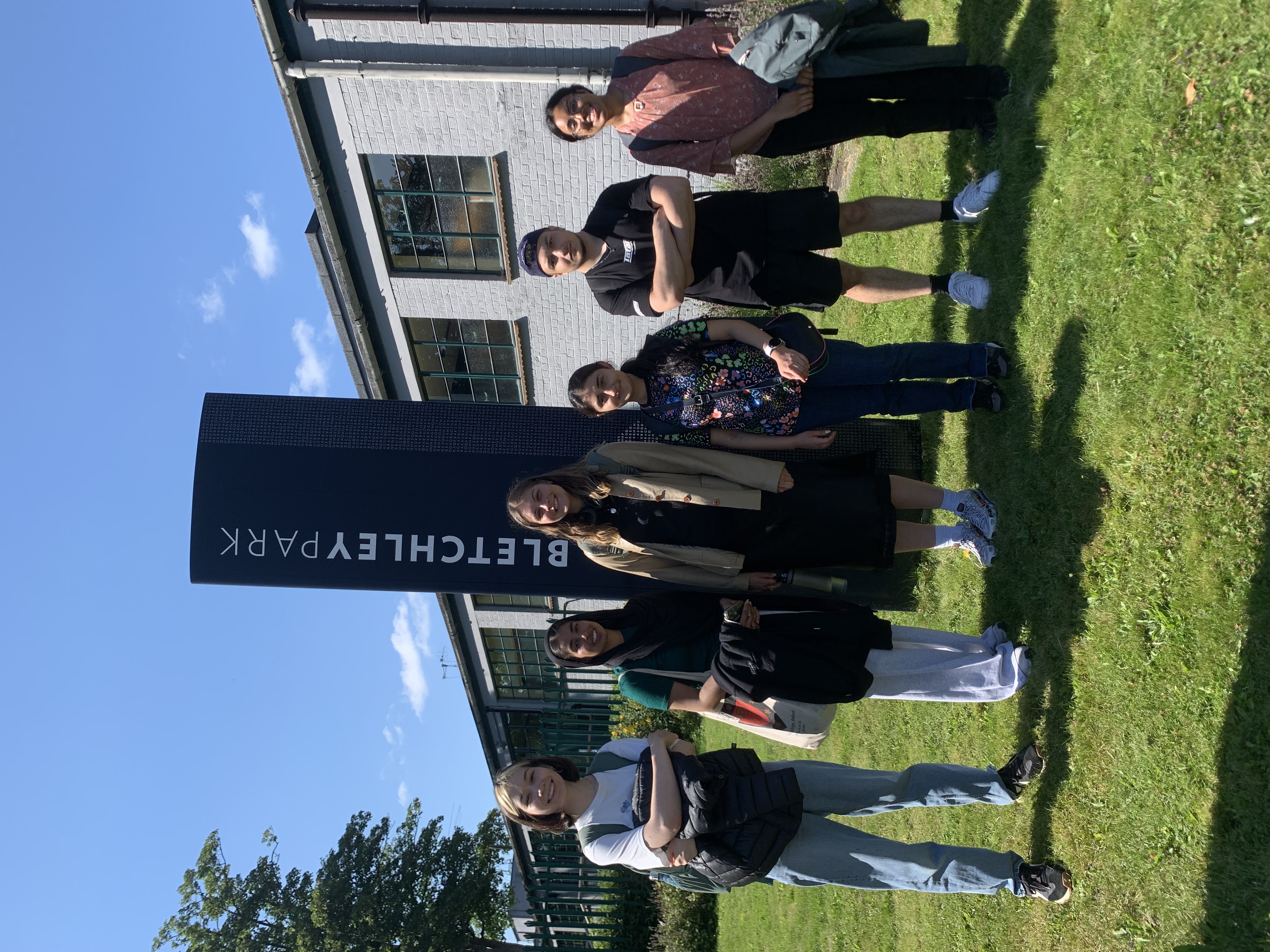 6 undergraduate students starting in front of the Bletchley Park sign on a sunny day