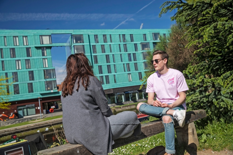 Students sitting by the canal on our Mile End campus