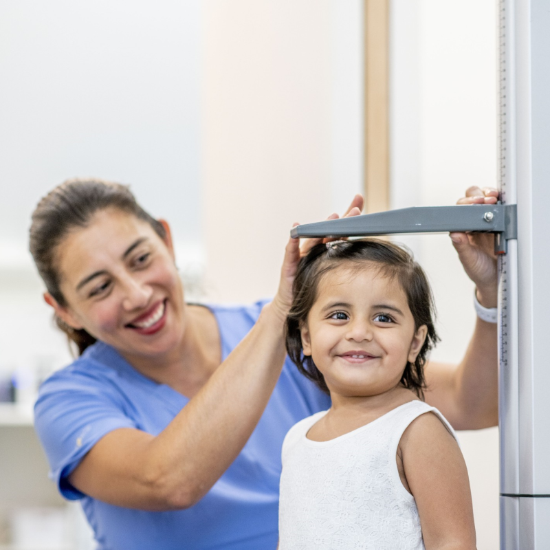 A child having their height measured by a nurse