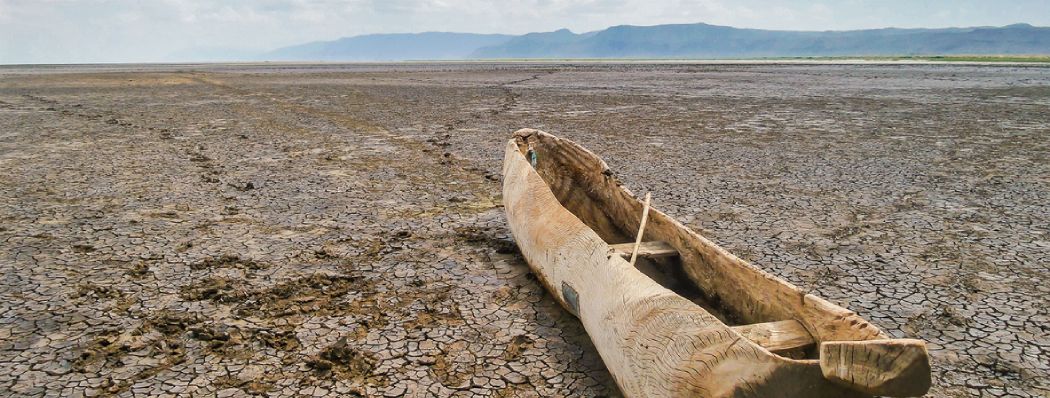 A boat sits on cracked earth in a dried out lake in Manyara National Park, Tanzania