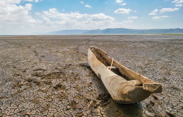 A boat sits on cracked earth in a dried out lake in Manyara National Park, Tanzania