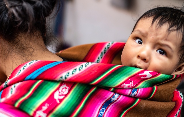 A Peruvian indigenous mother carries her baby son on her back in Cusco, Peru in March 2019