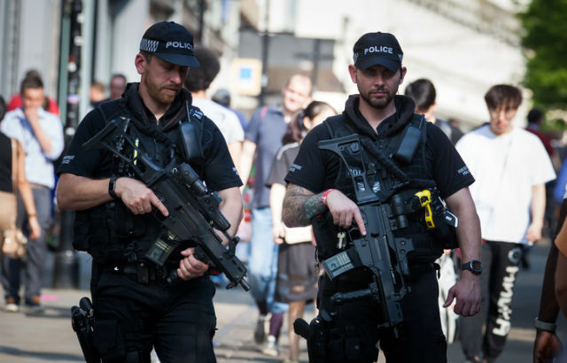 Armed police officers patrol a street in Manchester, England.