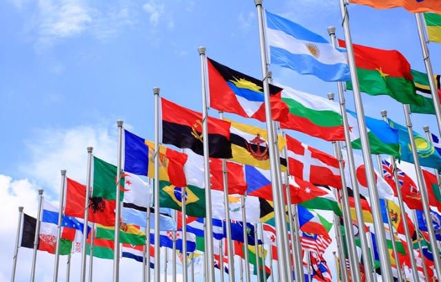 Flags of the world fly against a background of blue sky.