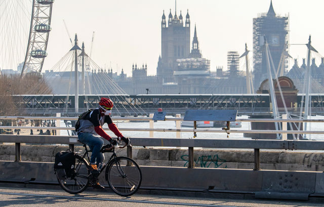 A cyclist wearing a facemask cycles past Parliament