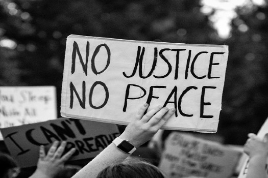 Someone holding a sign at a protest saying 'no justice, no peace'