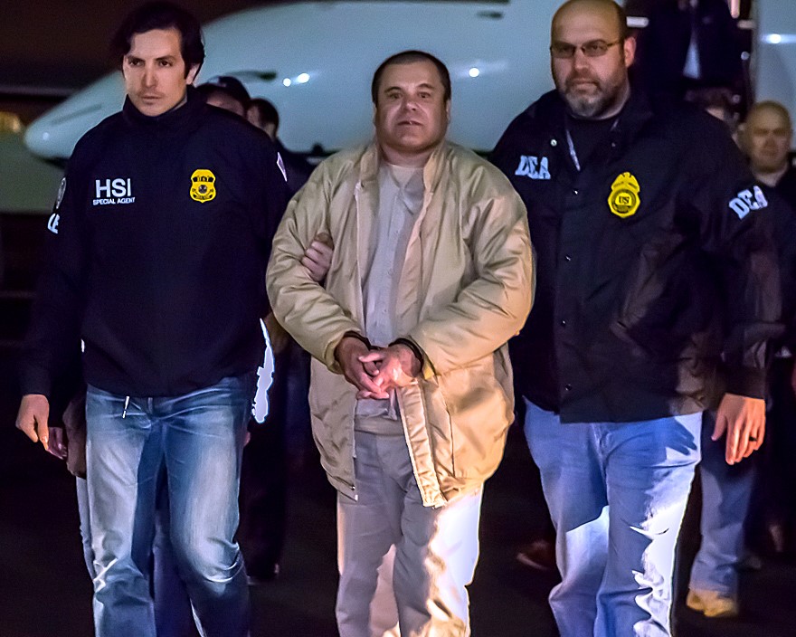 Mexican drug lord El Chapo being escorted by authorities. He is handcuffed.