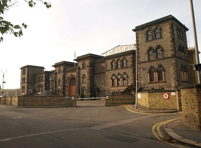 A picture of the exterior of HMP Wandsworth prison, London. It is a large brick building with a huge wooden door.