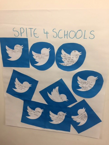 A white poster with several blue Twitter bird icons pasted on it with messages written inside them.