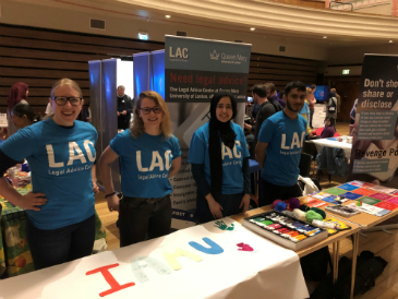 Four people stand at an exhibition table. They are wearing LAC t-shirts.