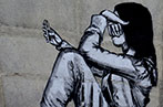 Graffiti on a wall of a girl looking sad using a phone