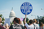 A pro-abortion protest with a person holding a sign saying 'keep abortion legal'